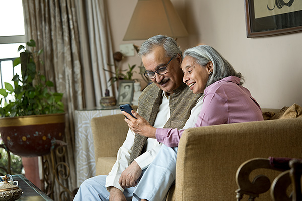 Ouder stel dat op de bank zit en naar smartphone kijkt